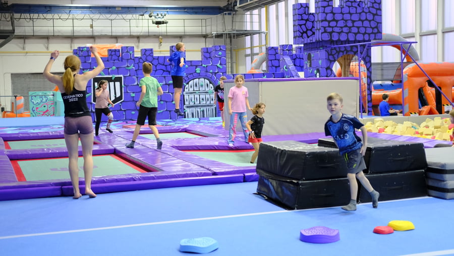 Děti skáčou na trampolínách a hrají si v UMPARK Ostrava – hrad a nafukovací atrakce v pozadí
