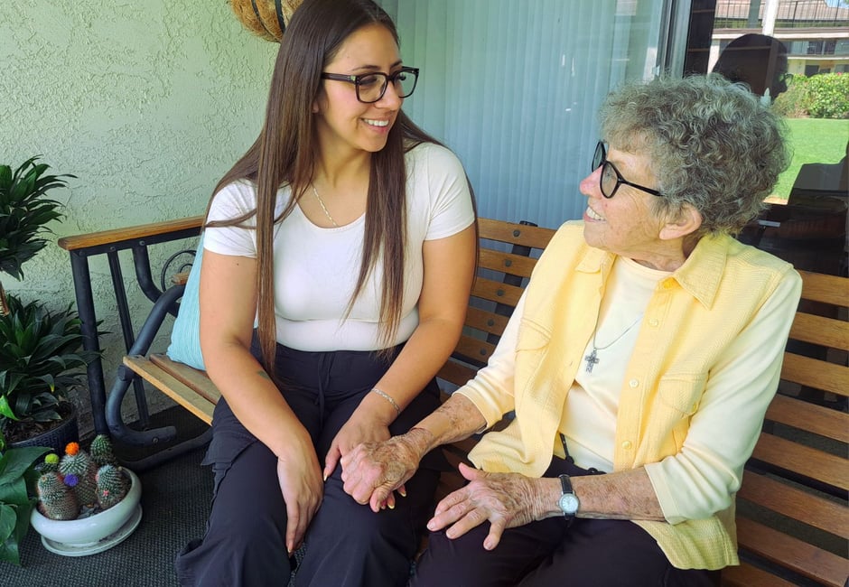 Coast Care caregiver sitting with an elderly client on a bench, sharing a warm conversation