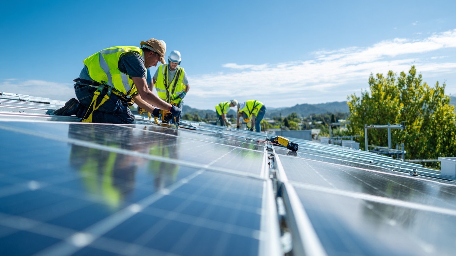 Montážní tým instalující fotovoltaické panely na střechu