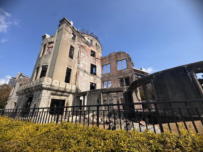 The Hiroshima Peace Memorial, the A-Bomb Dome, behind a low fence and green hedge