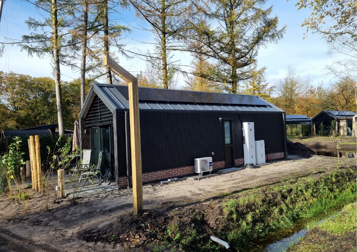 Zwart schuurtje met zonnepanelen op het dak en een thuisbatterij aan de zijmuur