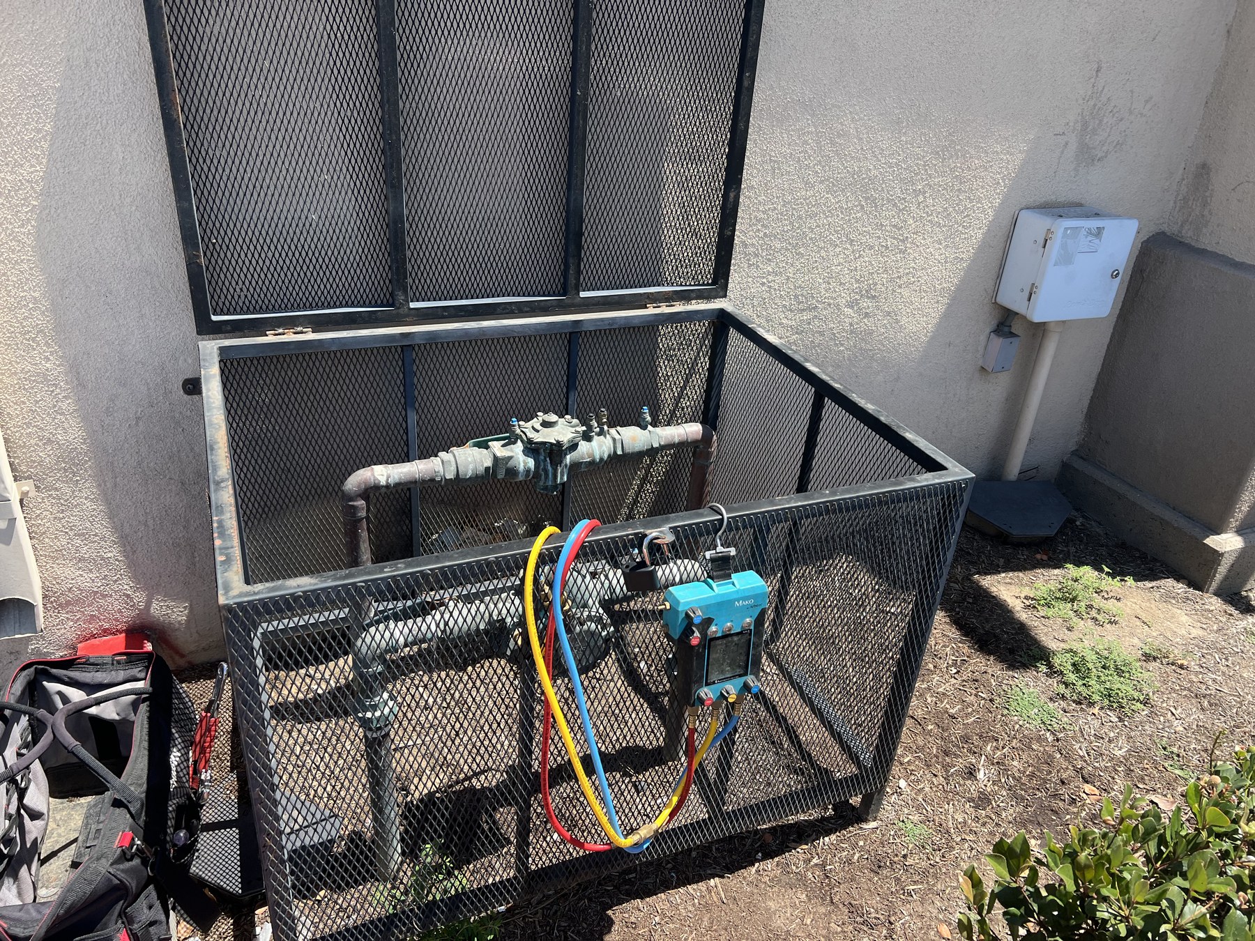 Backflow preventer inside a protective metal cage vault with test gauges attached — Anaheim CA