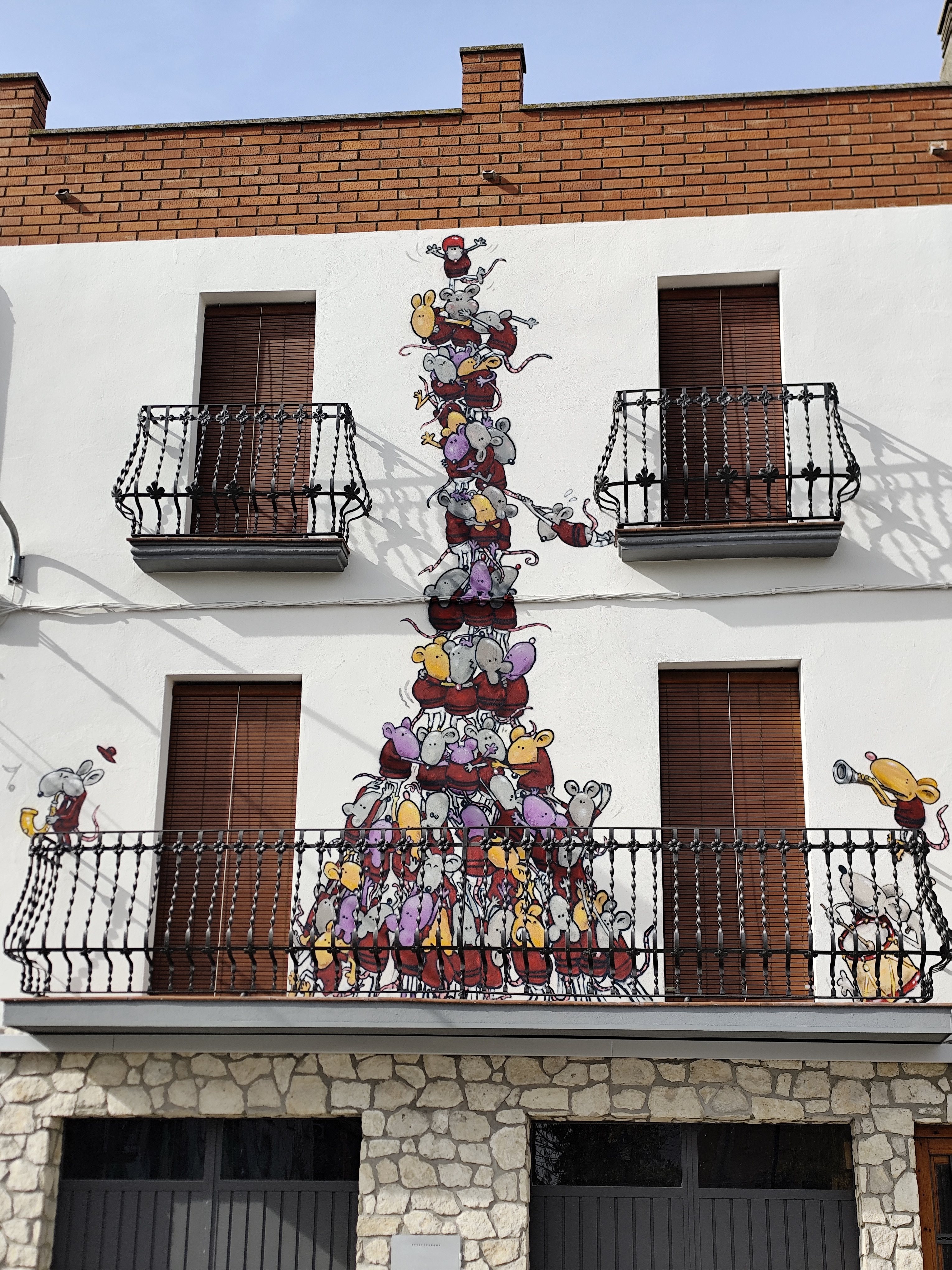 Mural de un rostro con tocado a rayas y una mano, Penelles