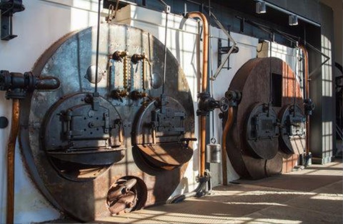 Row of large industrial stainless steel drum coffee roasters in a commercial facility