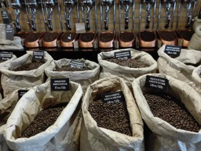 Display of multiple coffee bean varieties and ground coffee samples at a market or tasting