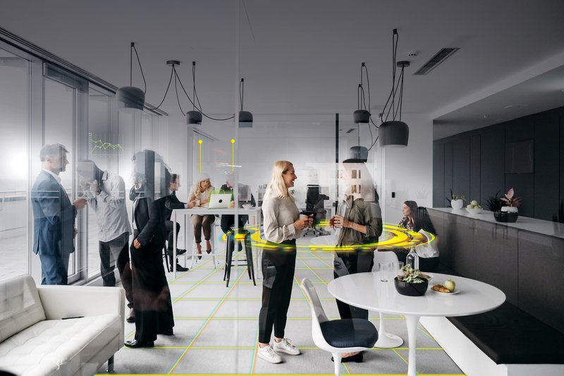 A photo of a company in everyday life in a modern office with large windows. They are smartly dressed and standing up having conversations. Horizontal daylight indoor photo.