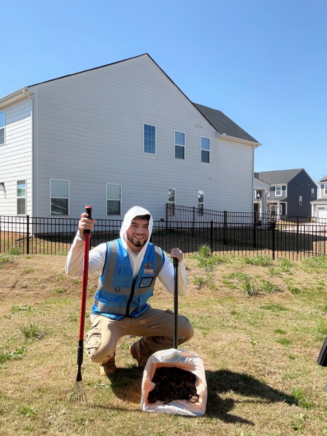 Technician kneeling next to a waste bin in front of a townhouse