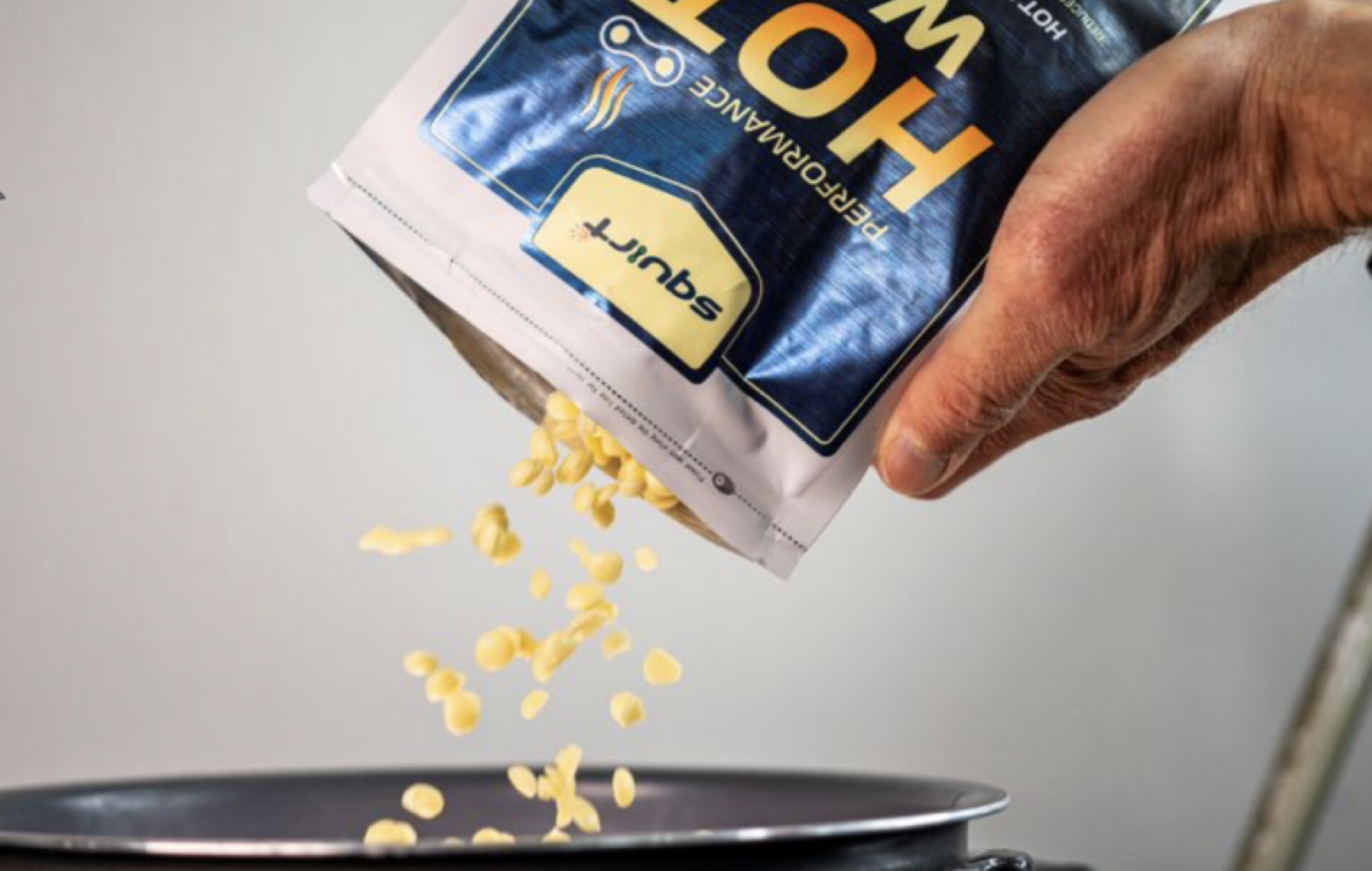 Hånd hælder Squirt Performance Hot Wax-piller fra posen i en gryde