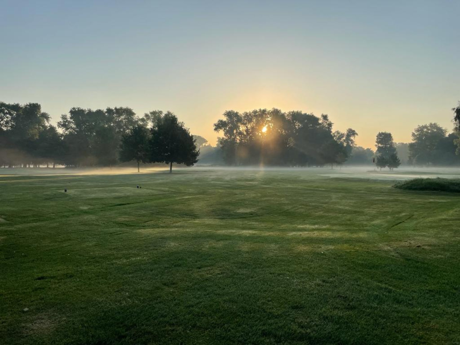 Golf Club Poděbrady při východu slunce s ranní mlhou nad fairwayem