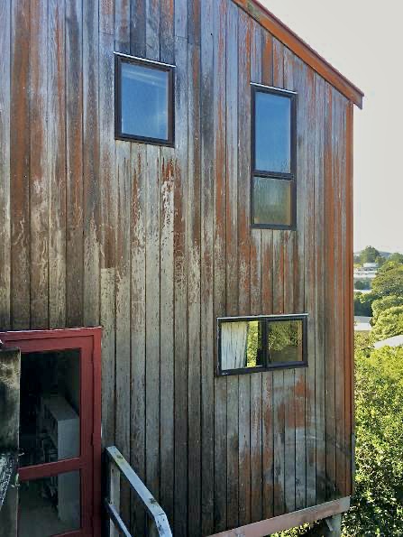 Dark stained cedar home with scaffolding set up among native bush