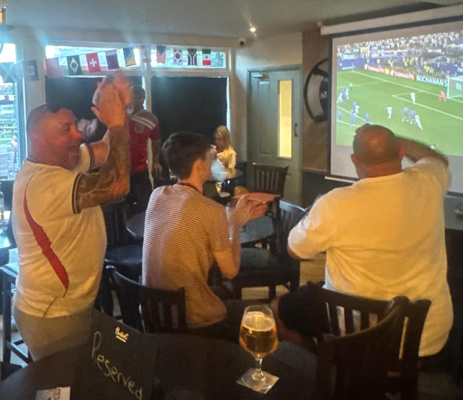 Fans cheering in front of the big screen during a match at The Star Inn