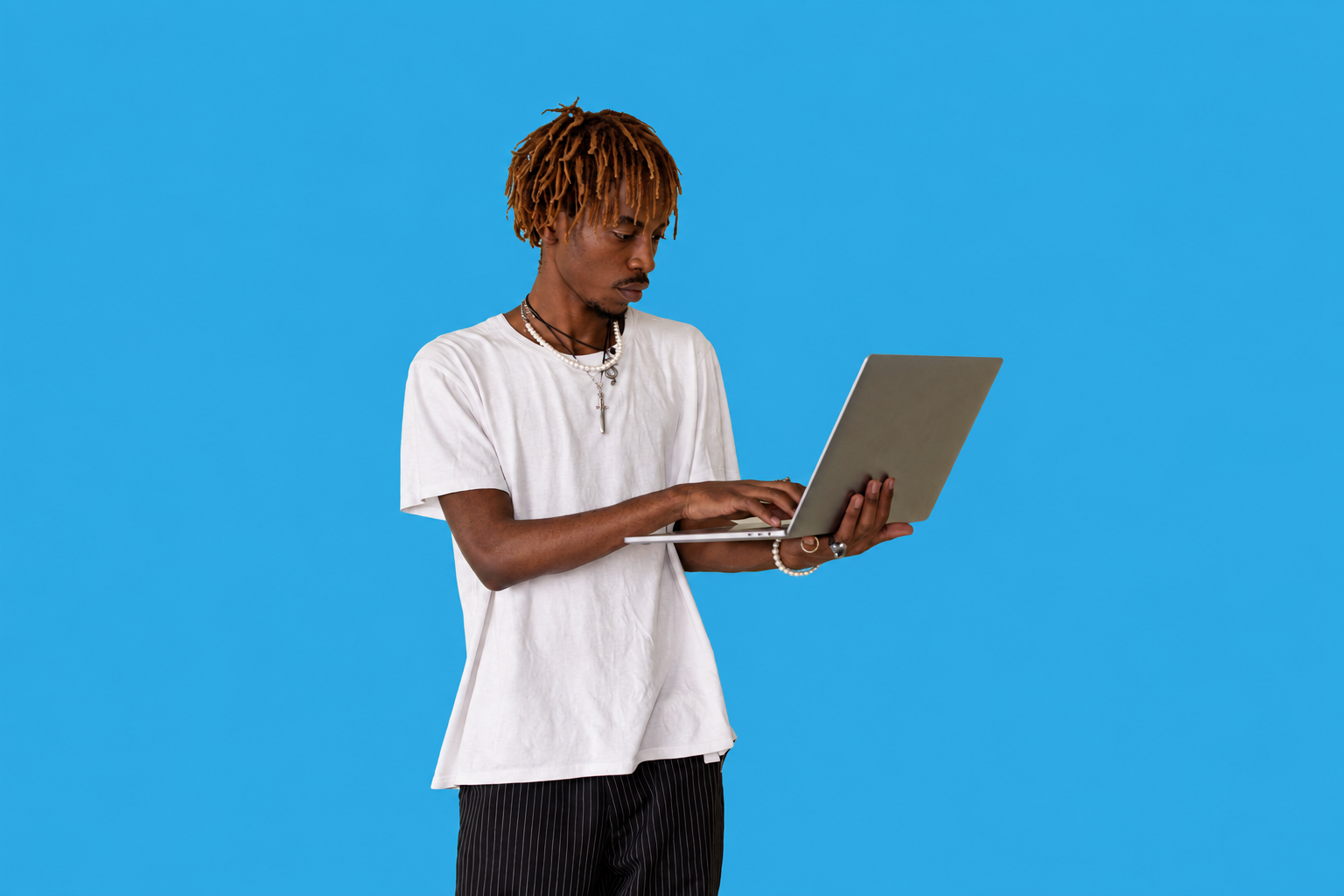Young man working on a laptop against a solid bright blue background