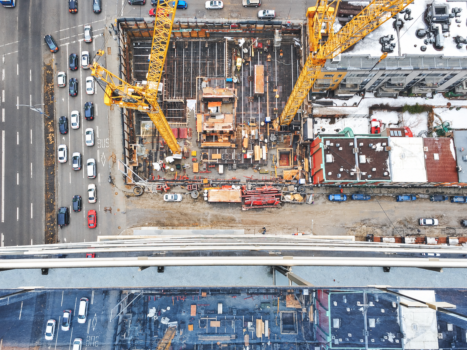 Aerial drone photo of a downtown high-rise construction site with tower cranes and rebar foundation