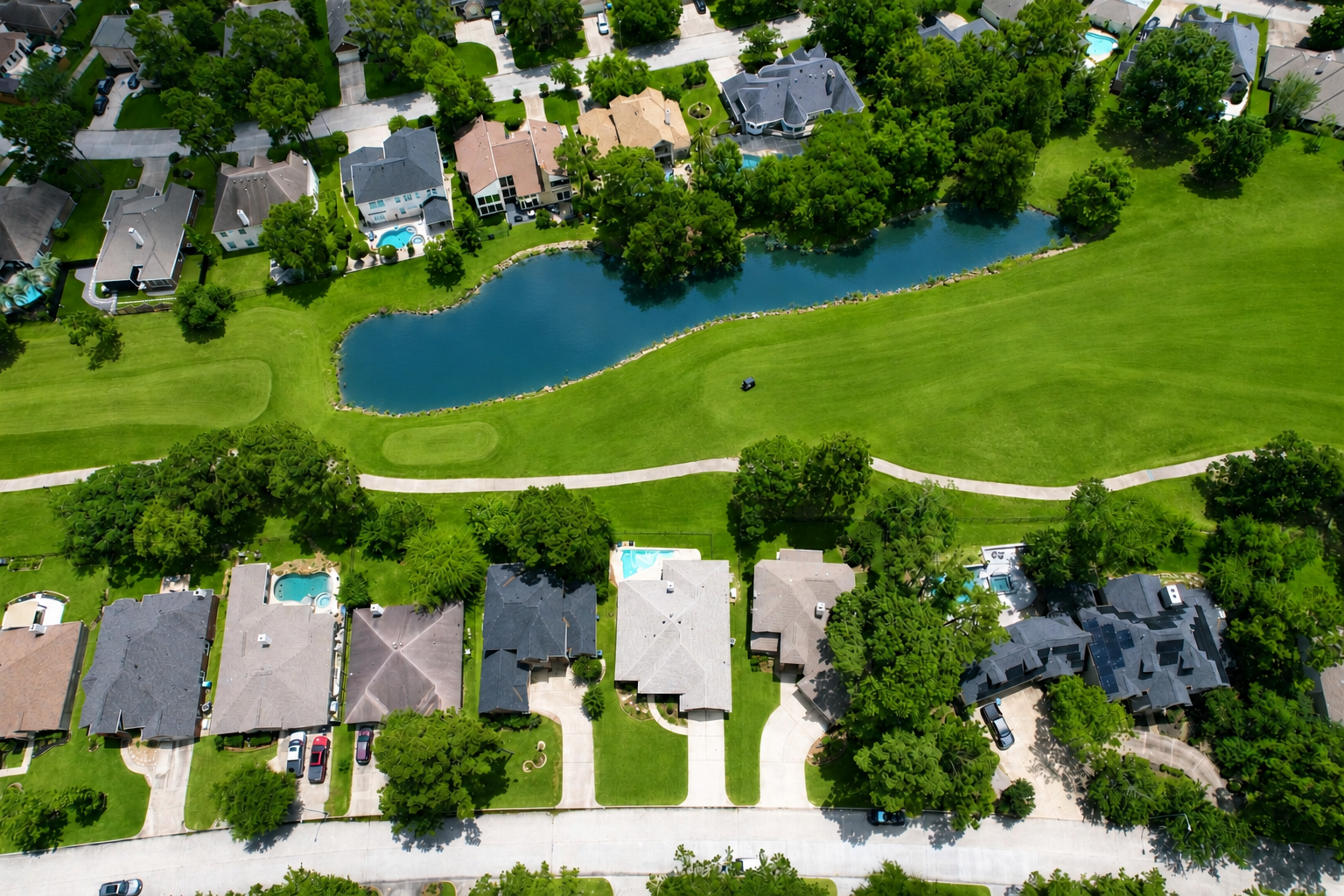 Aerial drone photo of a residential Houston neighborhood with golf course and lake for real estate marketing