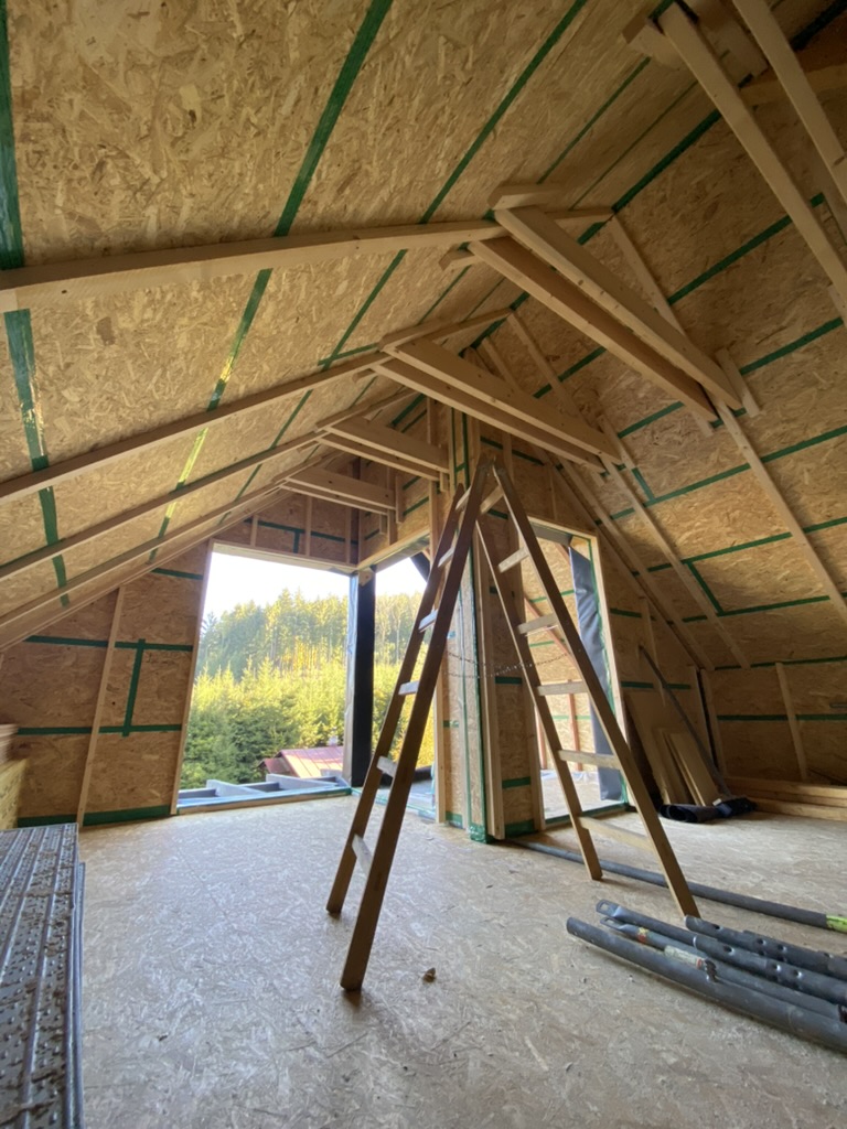 Interiér střechy chaty ve výstavbě – dřevěná konstrukce krovu s OSB deskami