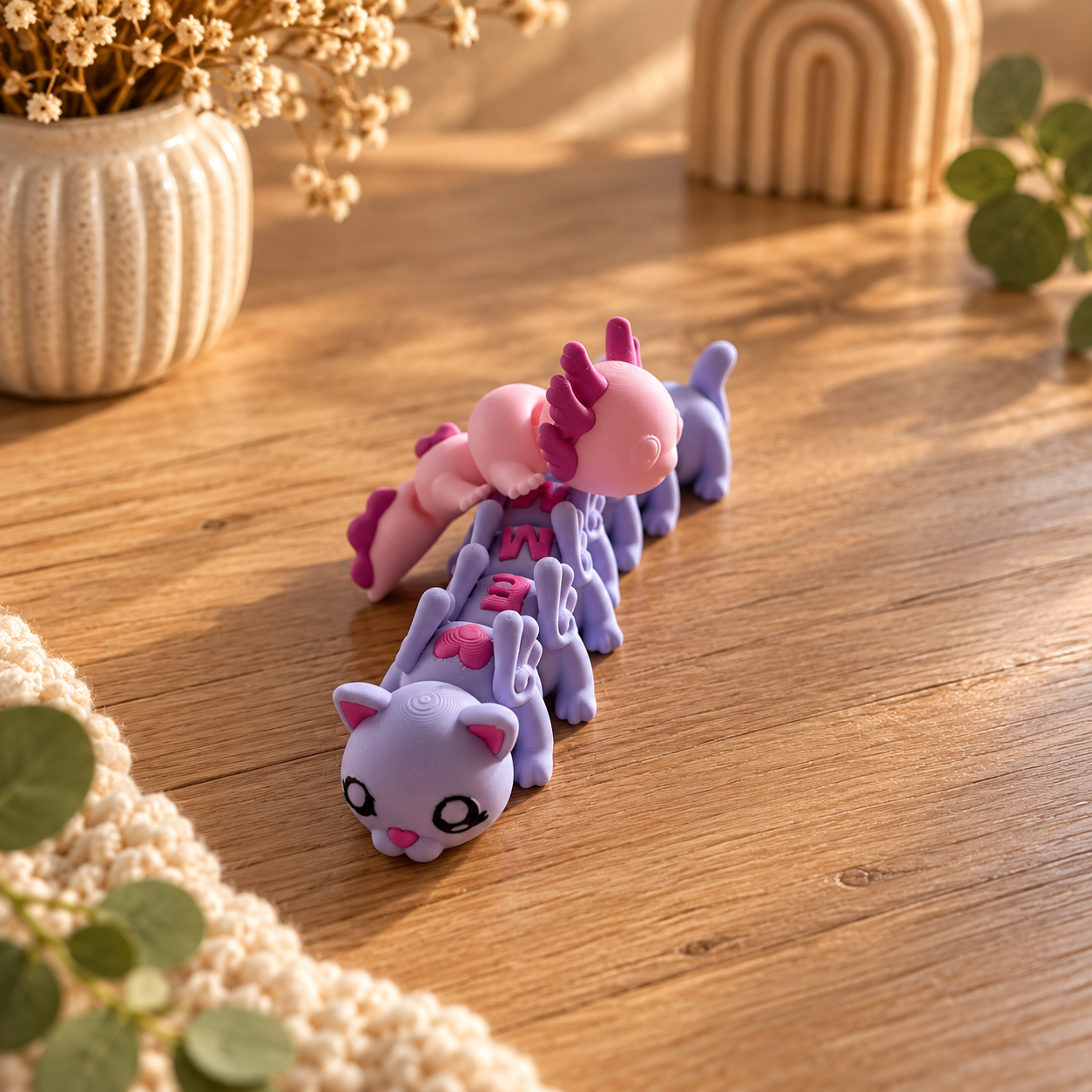 Geflexprinte 3D-diertjes van de Cutefleximaker: een lilakatje en een axolotl op een houten tafel