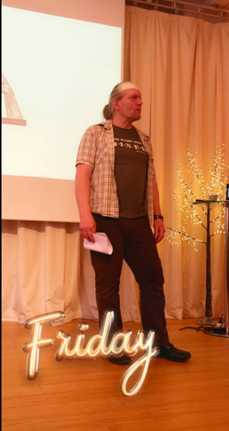 Jens Stardust smiler foran en lyserød væg med papirstjerner og et LOVE-skilt