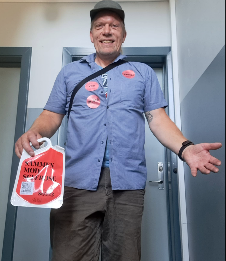 Jens Stardust smiler bredt med en rød 'Sammen mod sclerose'-indsamlingsboks
