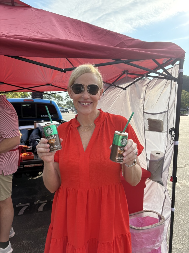 Fan in red smiling with a hand-crafted espresso drink under a tailgate canopy