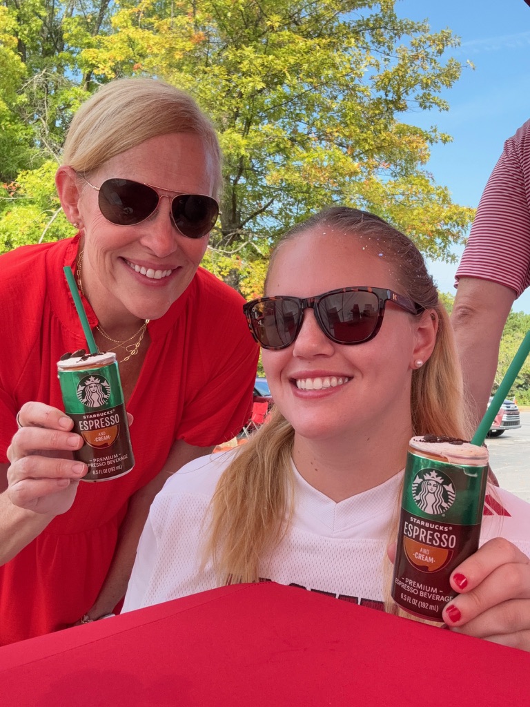 Two fans in red cheering on their team with hand-crafted espresso drinks at a Carolina football tailgate