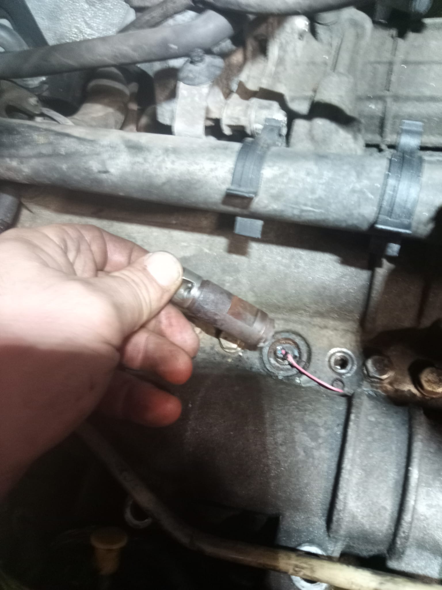 Vytažená špička žhaviče z hlavy motoru v ruce přímo na vozidle