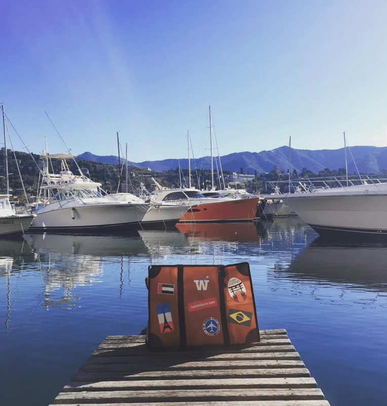 An orange WISSHH Travel Bag standing on a wooden dock at a marina
