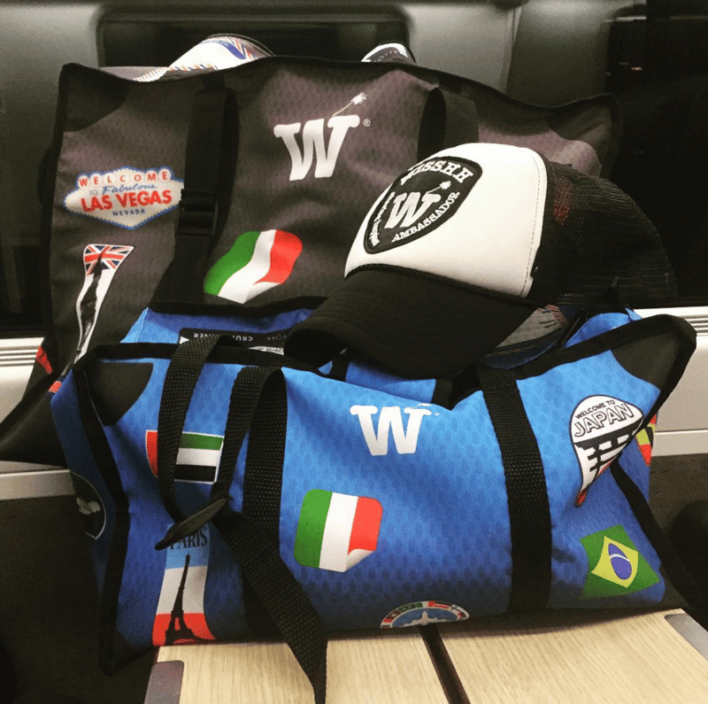 A blue WISSHH duffel with stickers and a WISSHH cap resting on a car seat