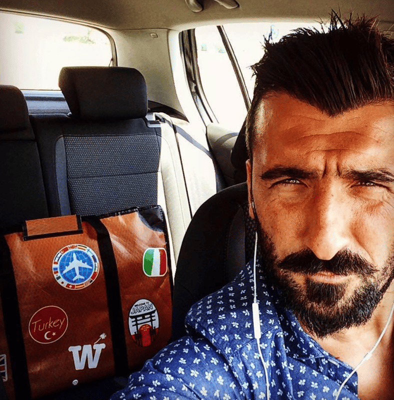 A bearded man taking a selfie in a car with an orange WISSHH Travel Bag on the seat