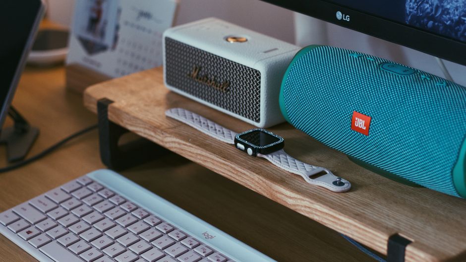 Moderne gadgets, smartwatch en draadloze speakers in sfeervolle werkruimte