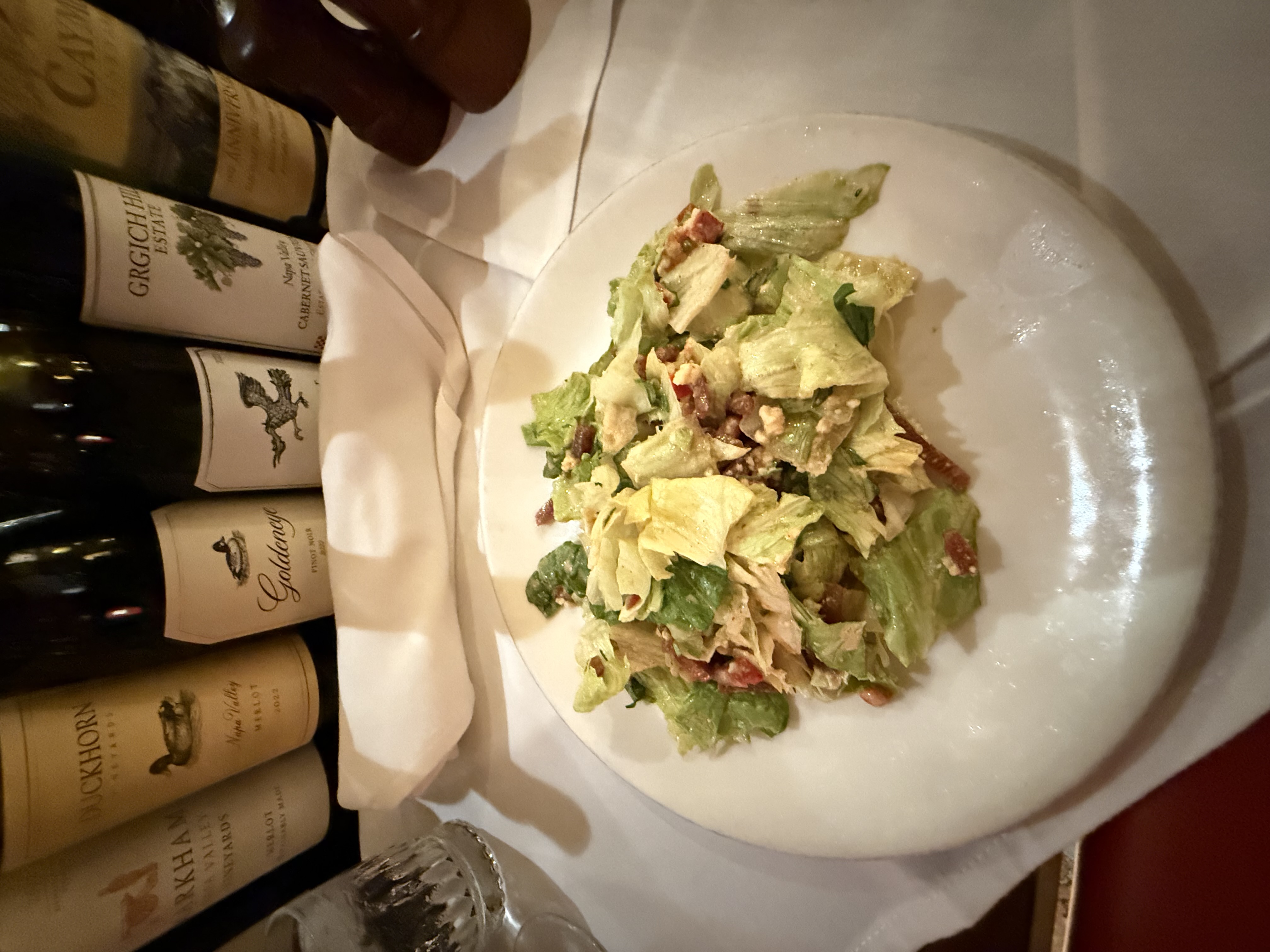 The chopped salad at the House of Prime Rib with Napa wine bottles lined up behind