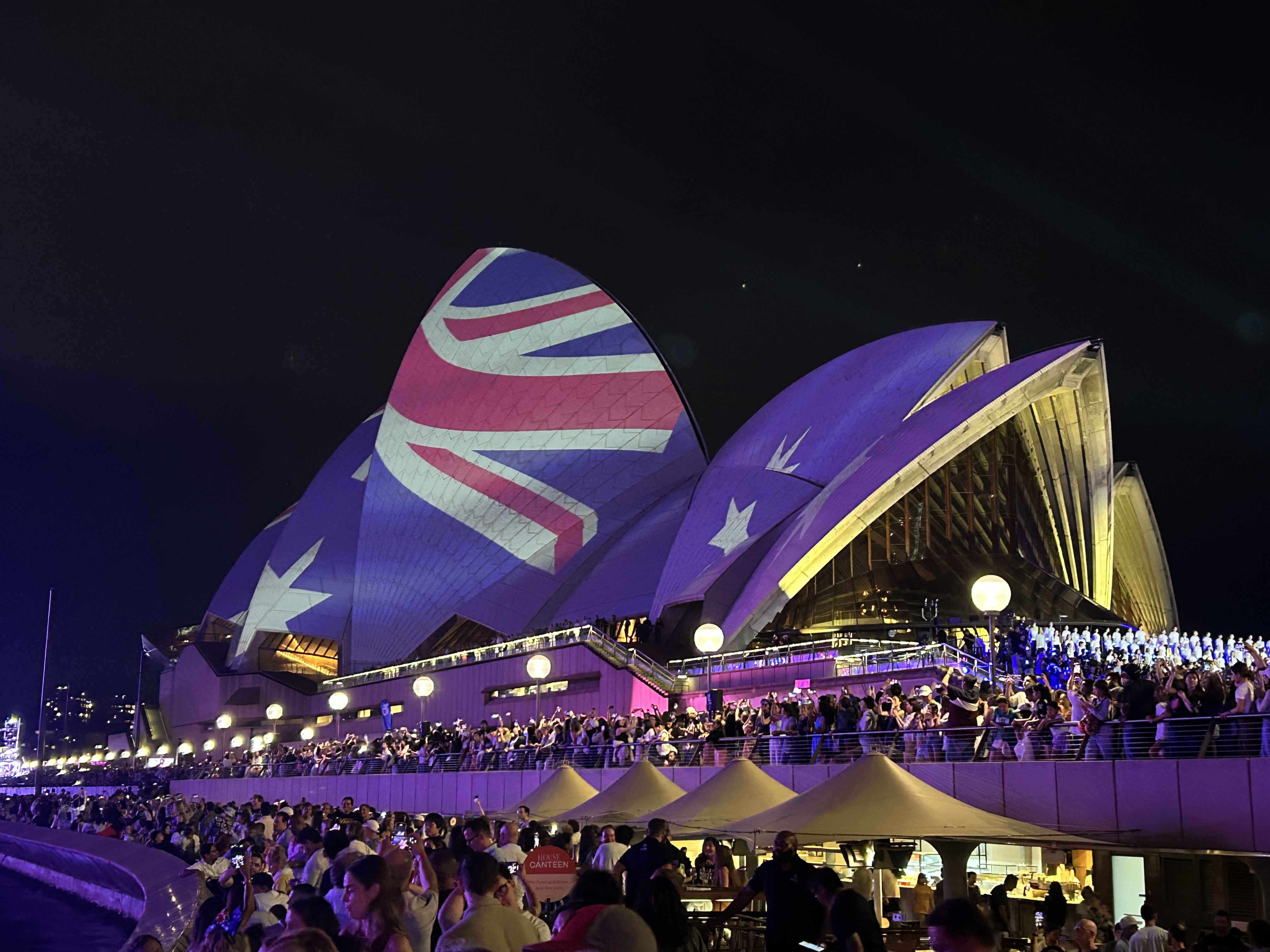 The Opera House sails lit up for Vivid Sydney, with the Australian flag projected on them.