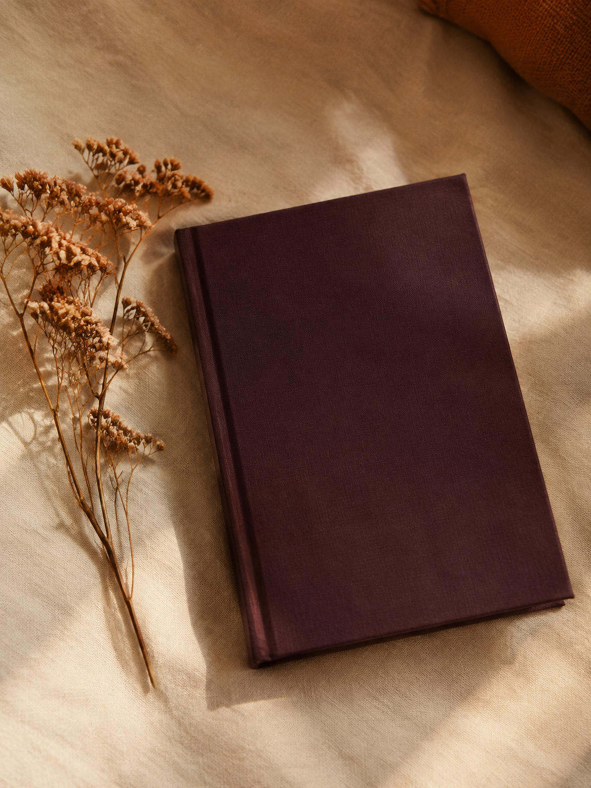Mørkeblommet hardcover bog på lærred ved siden af tørrede blomster