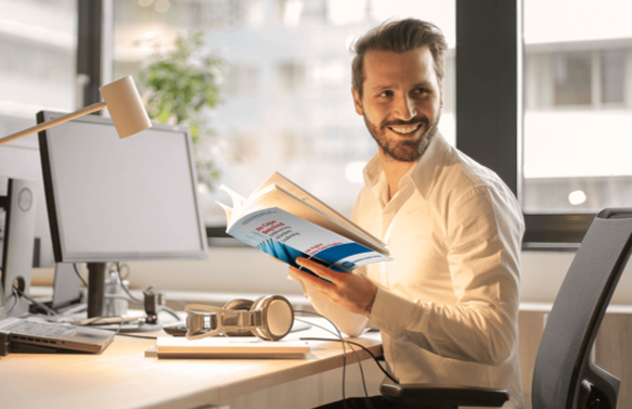 A smiling manager at his desk reading No Cape Required